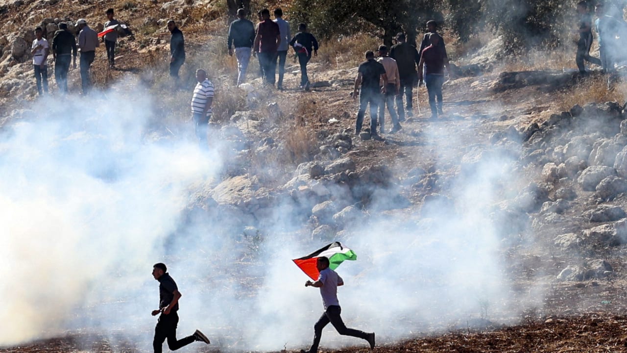 متظاهرون فلسطينيون يركضون من قنابل الغاز المسيل للدموع التي أطلقتها القوات الإسرائيلية على مظاهرة بالضفة الغربية