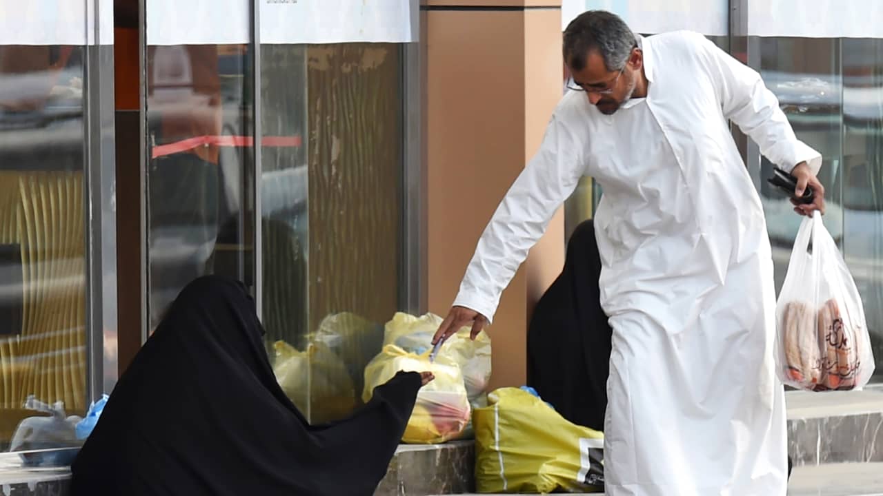 صورة ارشيفية لرجل يعطي مالا لامرأة تطلب المساعدة في السعودية