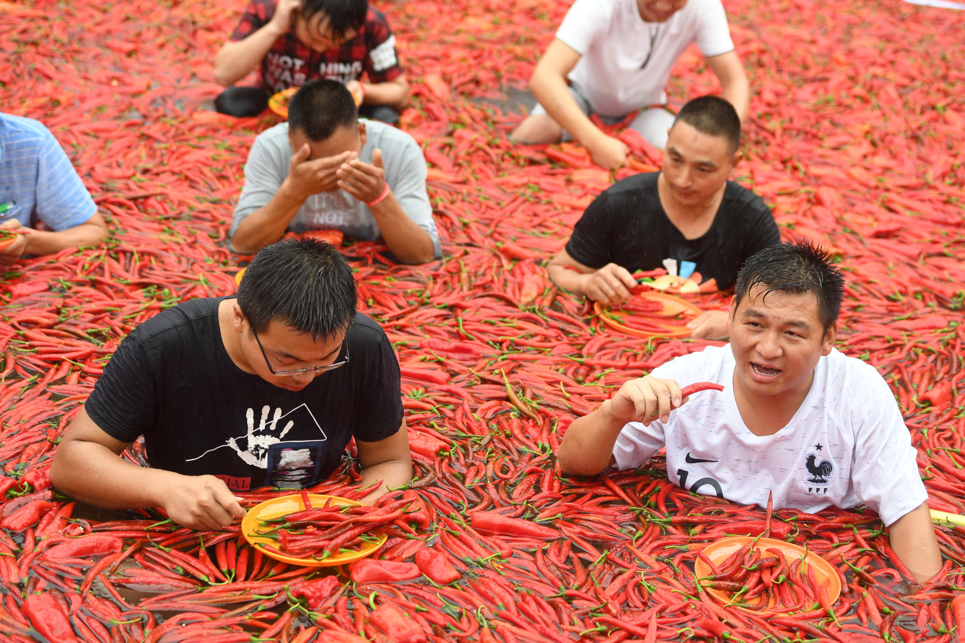 أشخاص يقفون في بركة مغطاة بالفلفل الحار أثناء مسابقة لتناوله في نينغشيانغ بمقاطعة هونان الصينية