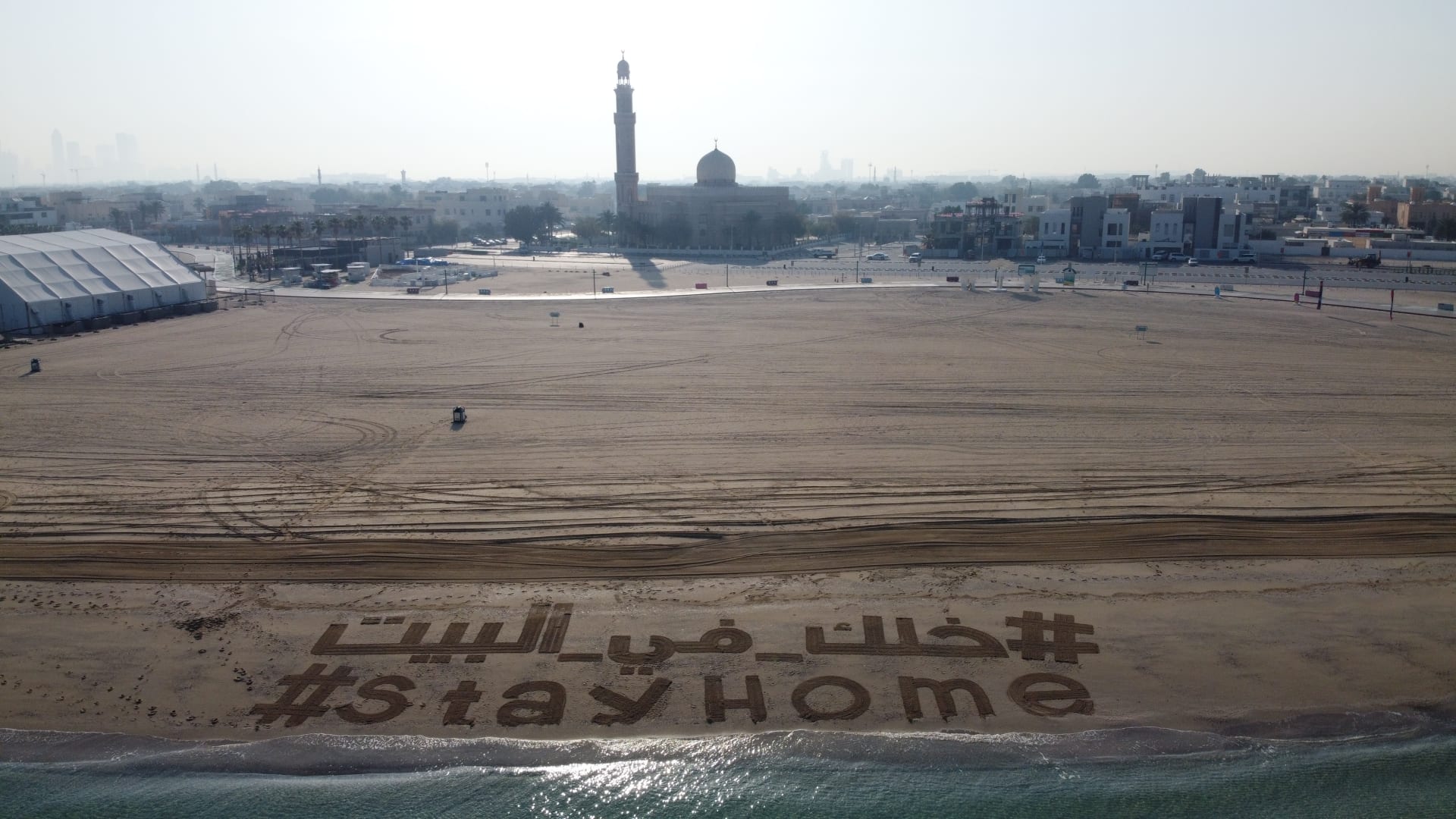 عبارة "خلك في البيت" تزين أحد شواطئ دبي