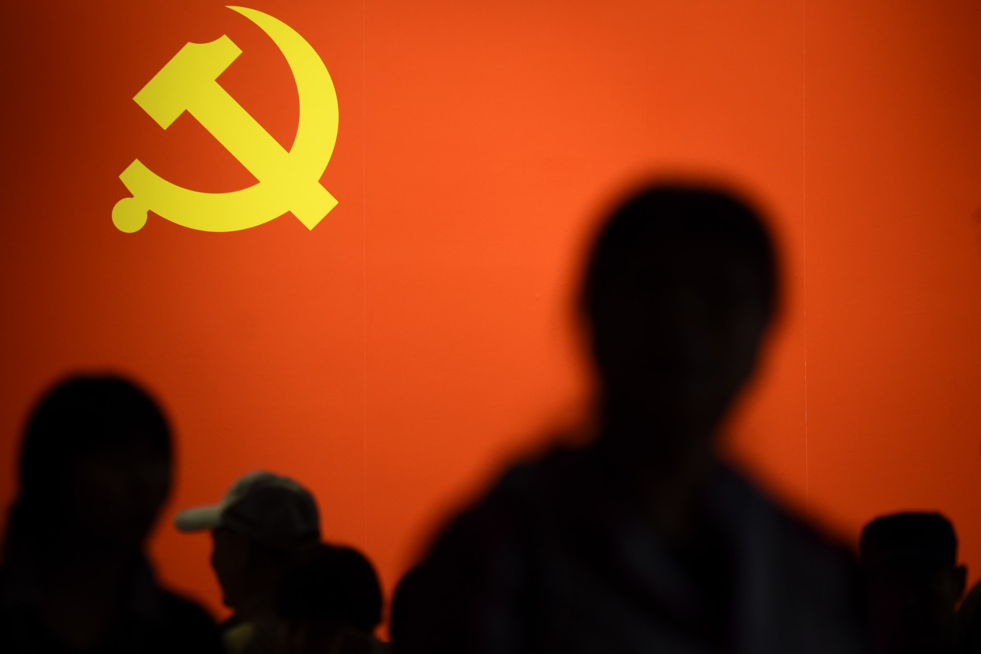 صورة أرشيفية لأشخاص يمرون أمام راية الحزب الشيوعي في الصين