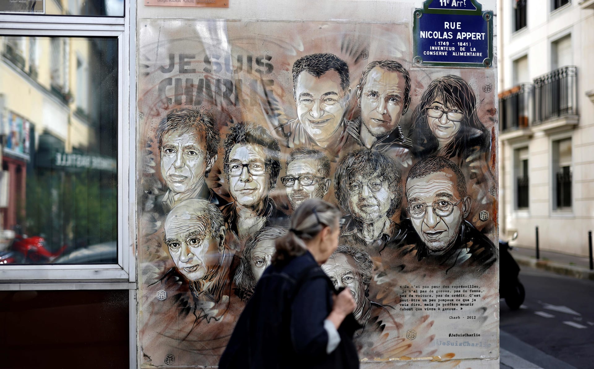 سيدة تمر بجوار لافتة تحيي ذكرى الضحايا في الهجوم على مقر صحيفة شارلي إبدو الفرنسية في 2015
