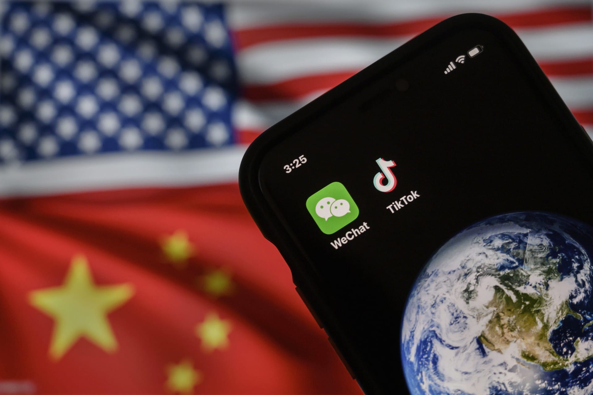 رسم يبيّن هاتفاً محمولاً يعرض تطبيقي WeChat و TikTok أمام شاشة تعرض علمي الولايات المتحدة والصين