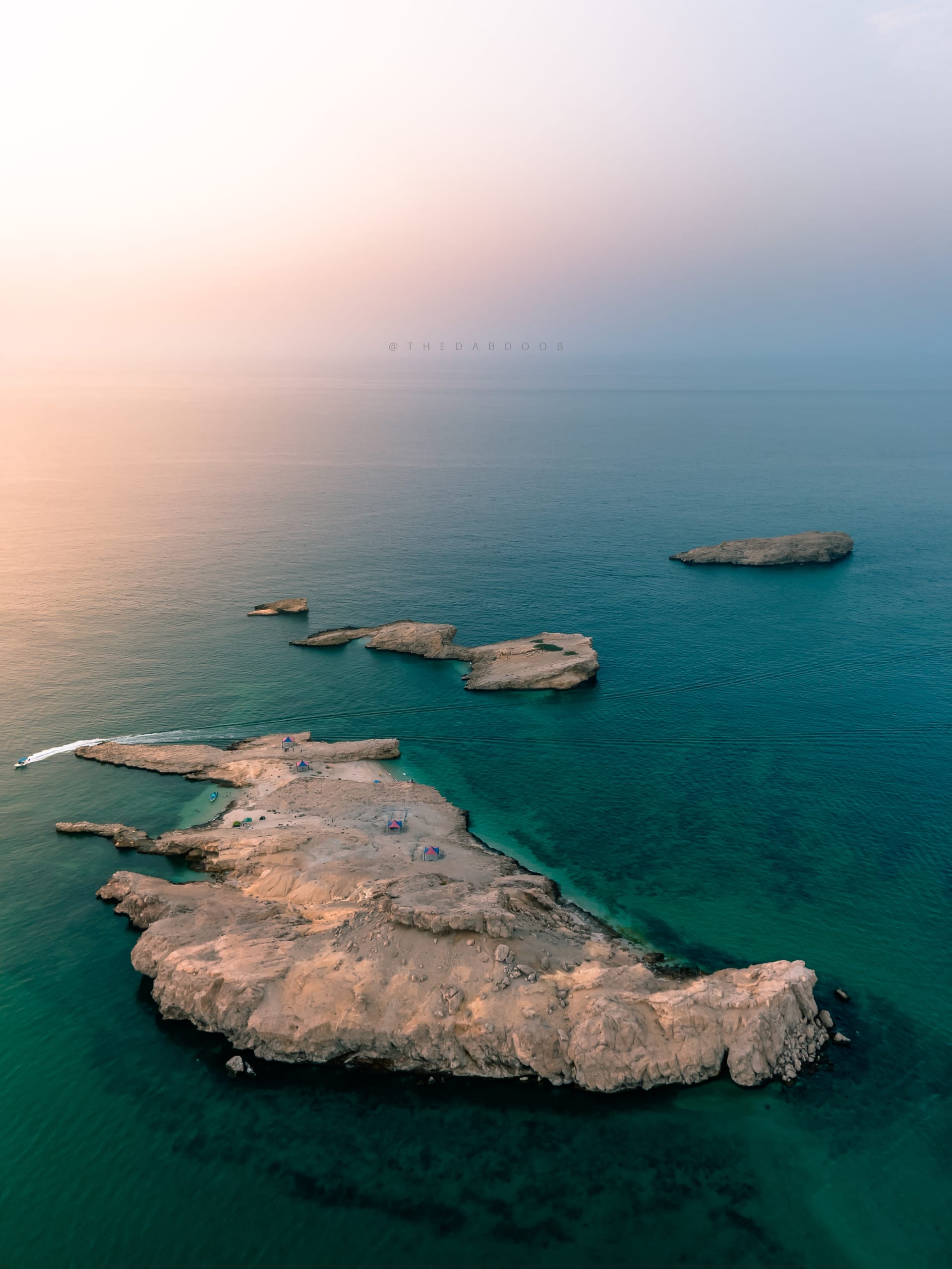 مشهد مهيب..عمانية توثق جزر صخرية بإحدى أهم شواطئ سلطنة عمان عاليًا من السماء