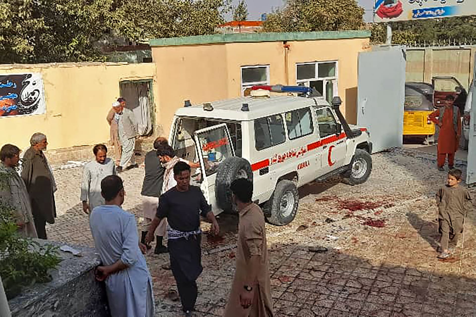 رجال أفغان يقفون بجوار سيارة إسعاف بعد هجوم بقنبلة على مسجد في قندوز، في 8 أكتوبر 2021