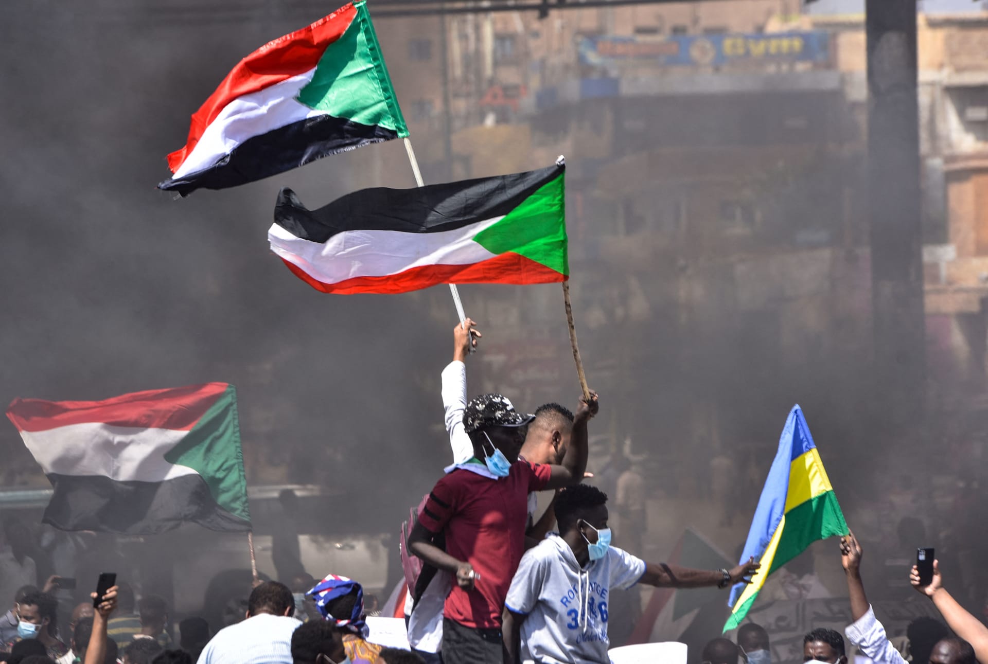 متظاهرون سودانيون يرفعون الأعلام الوطنية أثناء مشاركتهم في احتجاج بمدينة الخرطوم بحري، المدينة التوأم الشمالية للعاصمة، للمطالبة بانتقال الحكومة إلى الحكم المدني، في 21 أكتوبر / تشرين الأول 2021.