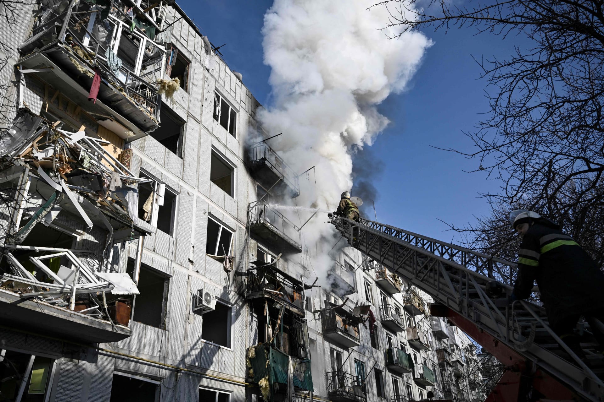 رجال إطفاء يعملون على حريق في مبنى بعد قصف روسي لبلدة تشوغويف بشرق أوكرانيا