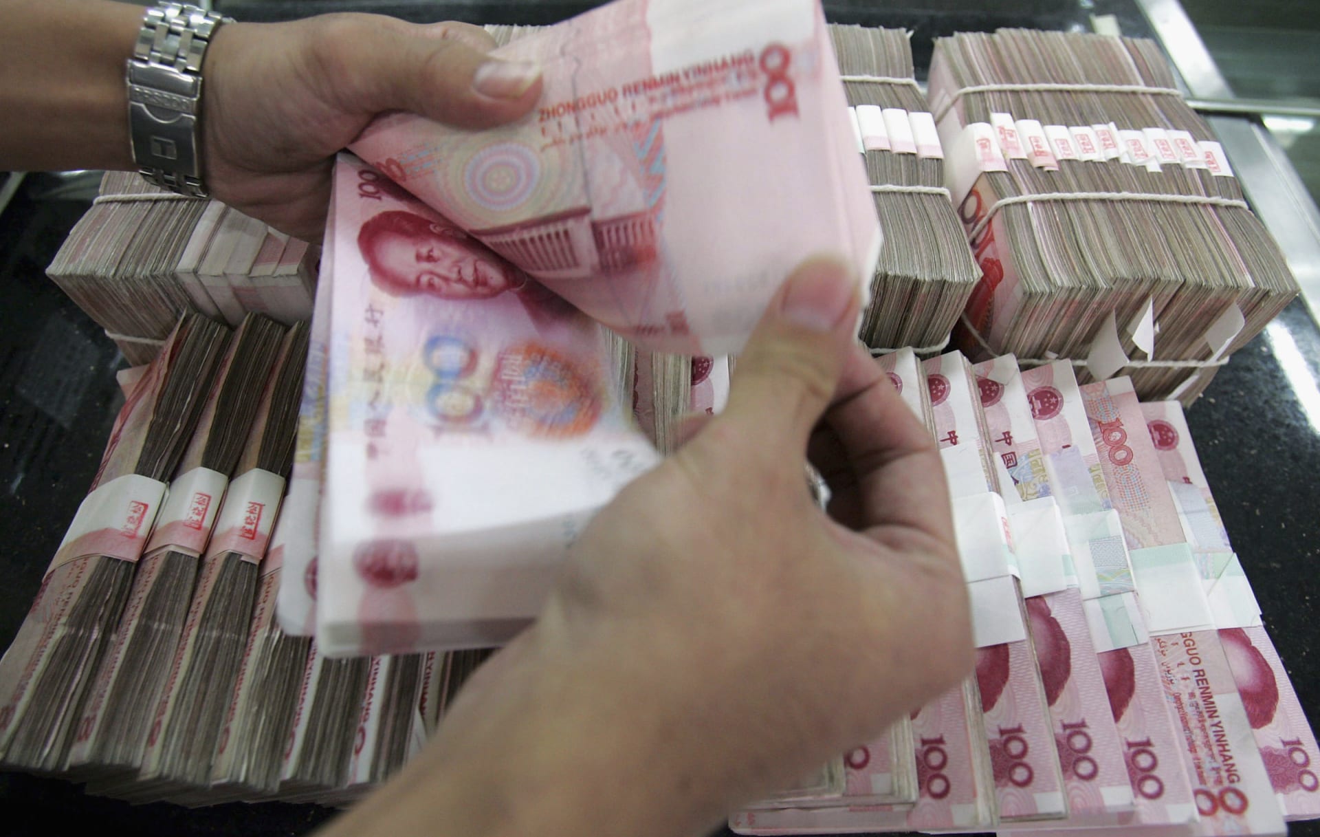 شخص يعد مجموعة من أوراق نقد اليوان الصيني في أحد بنوك بكين (صورة أرشيفية)
