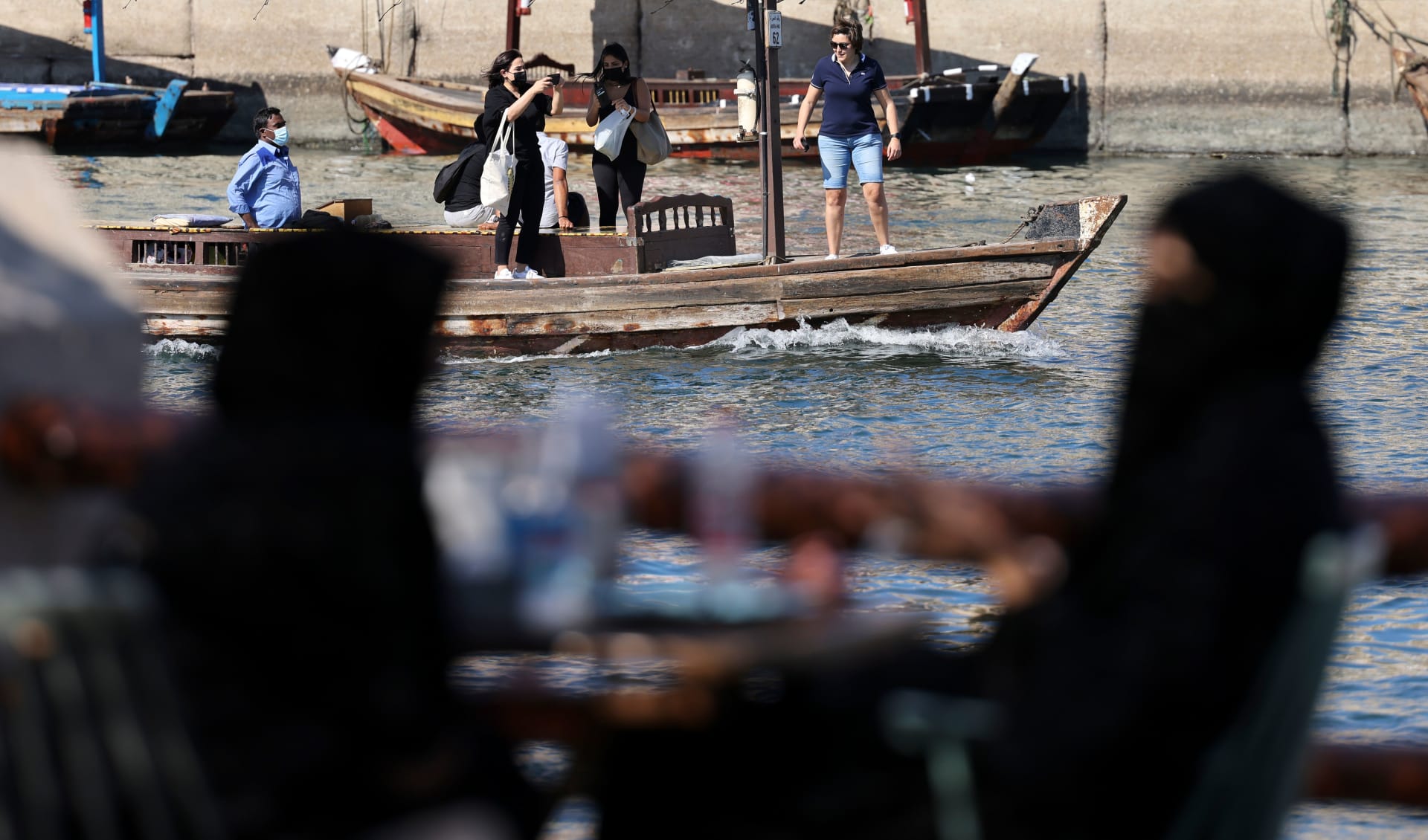 إماراتيات ينظرن إلى قارب يحمل مجموعة سائحين في محمية رأس الخور للحياة البرية في دبي