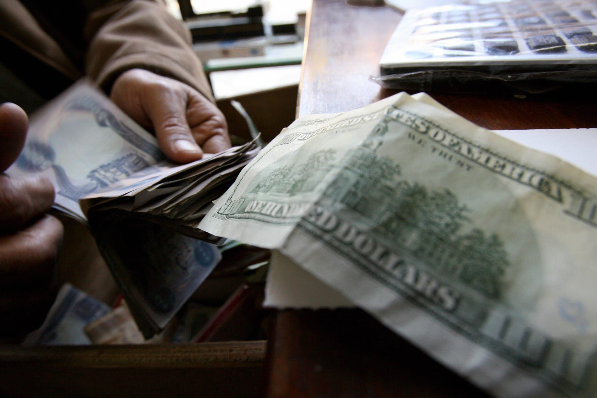 صورة أرشيفية العام 2007 لرجل يعد نقودا عراقية أمام ورقة 100 دولار 