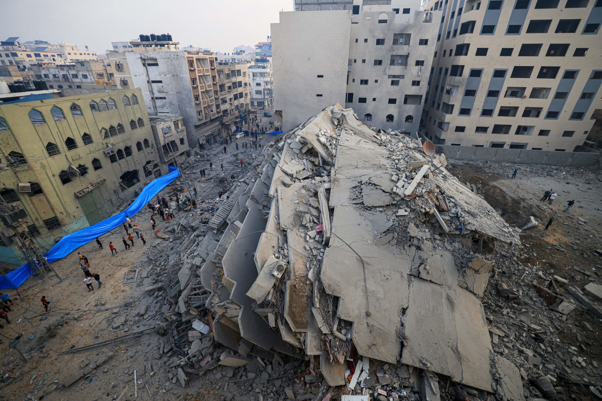 أشخاص يتجولون حول أنقاض مبنى دمر في الغارات الإسرائيلية في مدينة غزة في 8 أكتوبر 2023