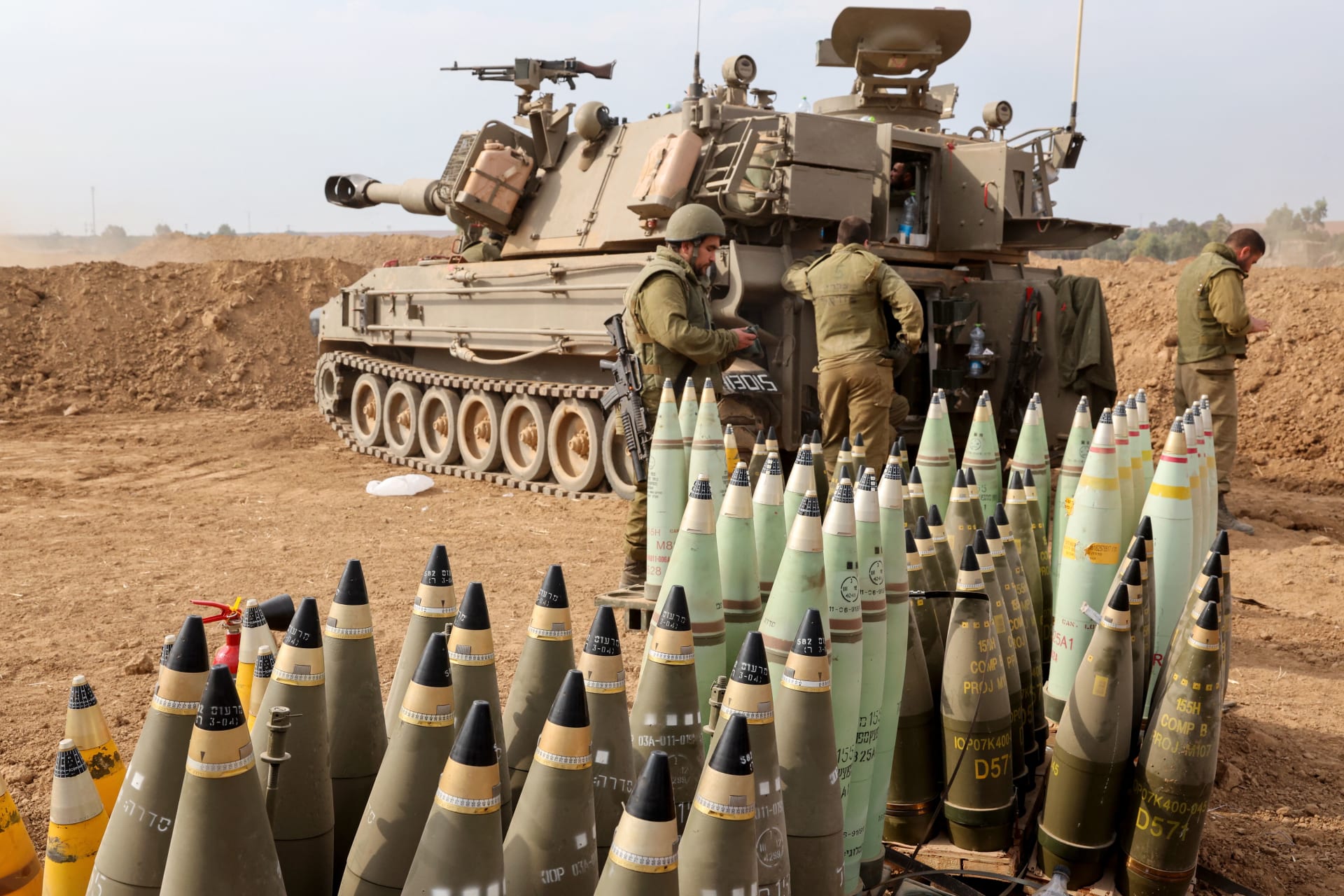 قذائف مدفعية مصطفة بجوار مركبة مدرعة بينما يتخذ الجنود الإسرائيليون مواقعهم بالقرب من الحدود مع غزة في جنوب إسرائيل في 9 أكتوبر/ تشرين الأول 2023.