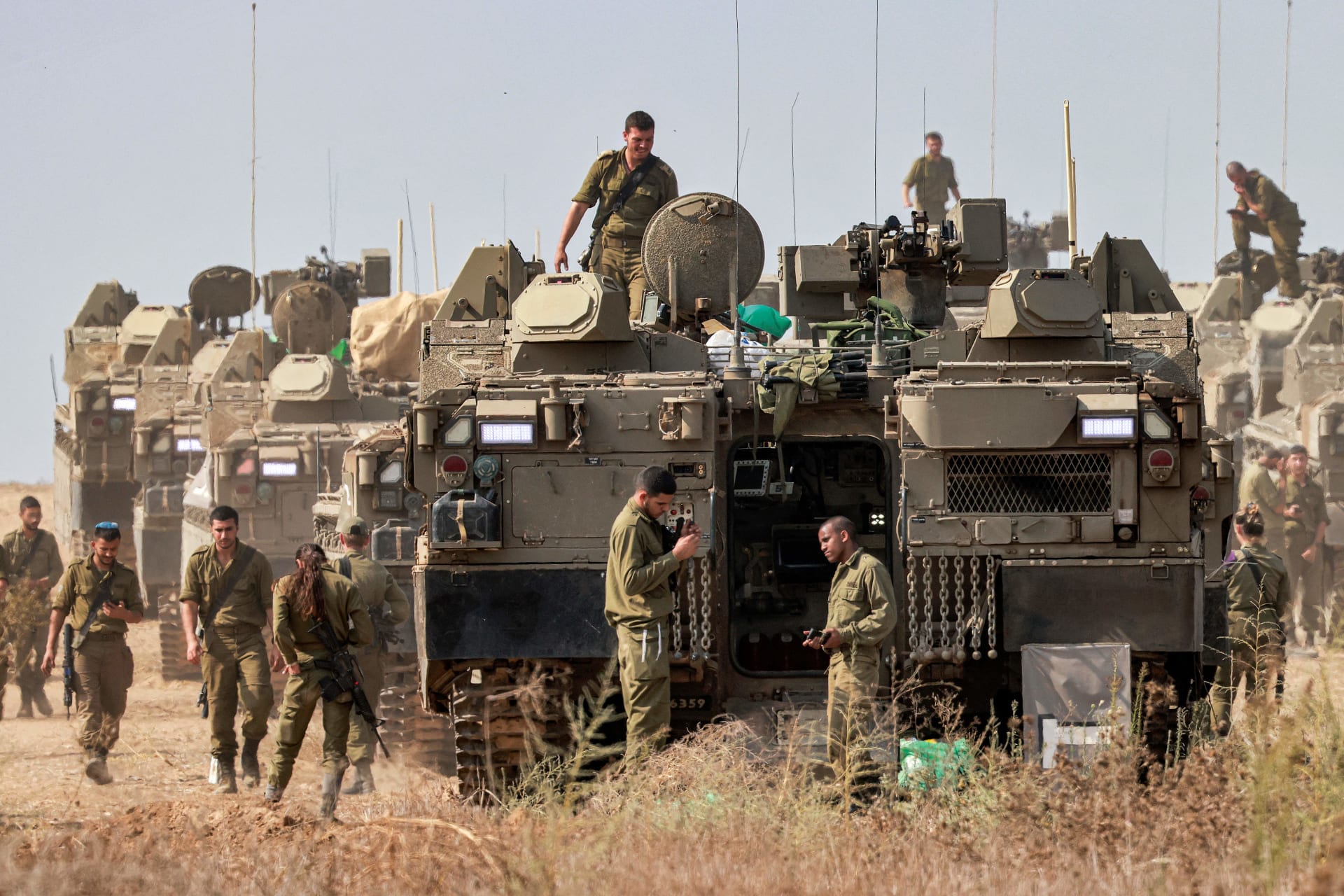 جنود الجيش الإسرائيلي يقفون بالقرب من ناقلات الجنود المدرعة نمر المتمركزة في موقع بالقرب من الحدود مع غزة في 11 أكتوبر/ تشرين الأول 2023.