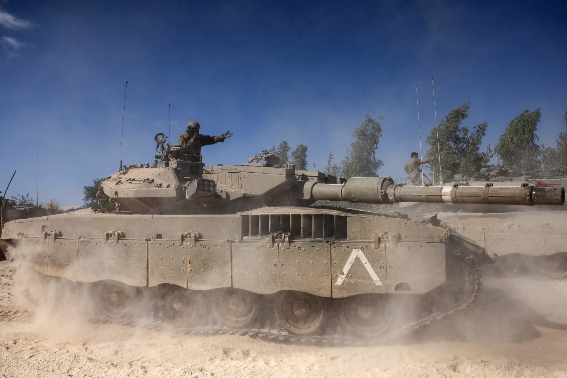 جندي إسرائيلي يعطي تعليمات من أعلى دبابة ميركافا المتمركزة خارج كيبوتس بيري بالقرب من الحدود مع قطاع غزة في 20 أكتوبر/ تشرين الأول 2023.