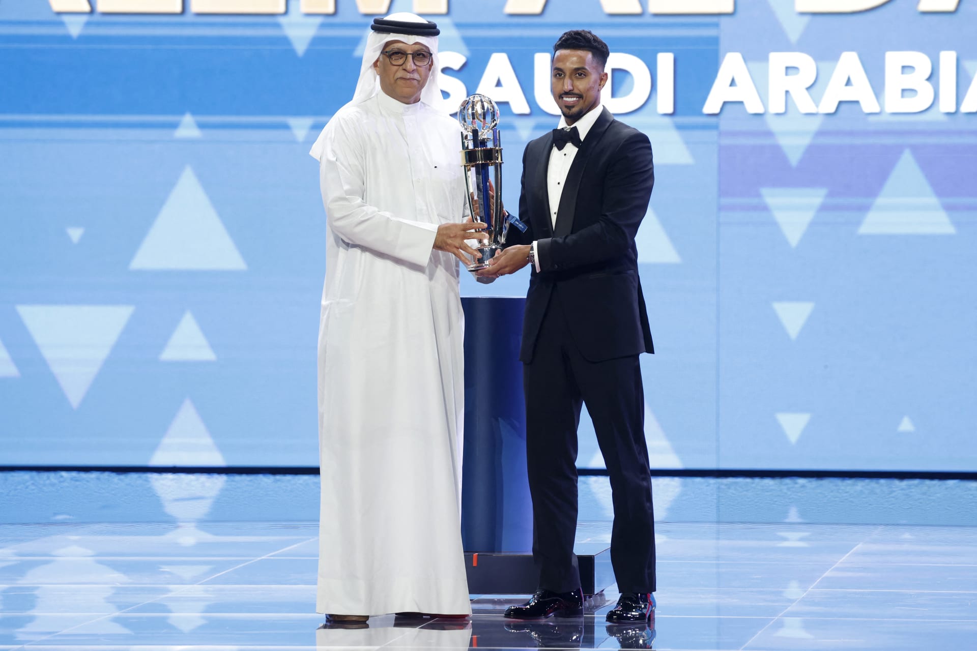اللاعب السعودي مرتديا بدلة رسمية كلاسيكية في الدوحة بالعام 2023.