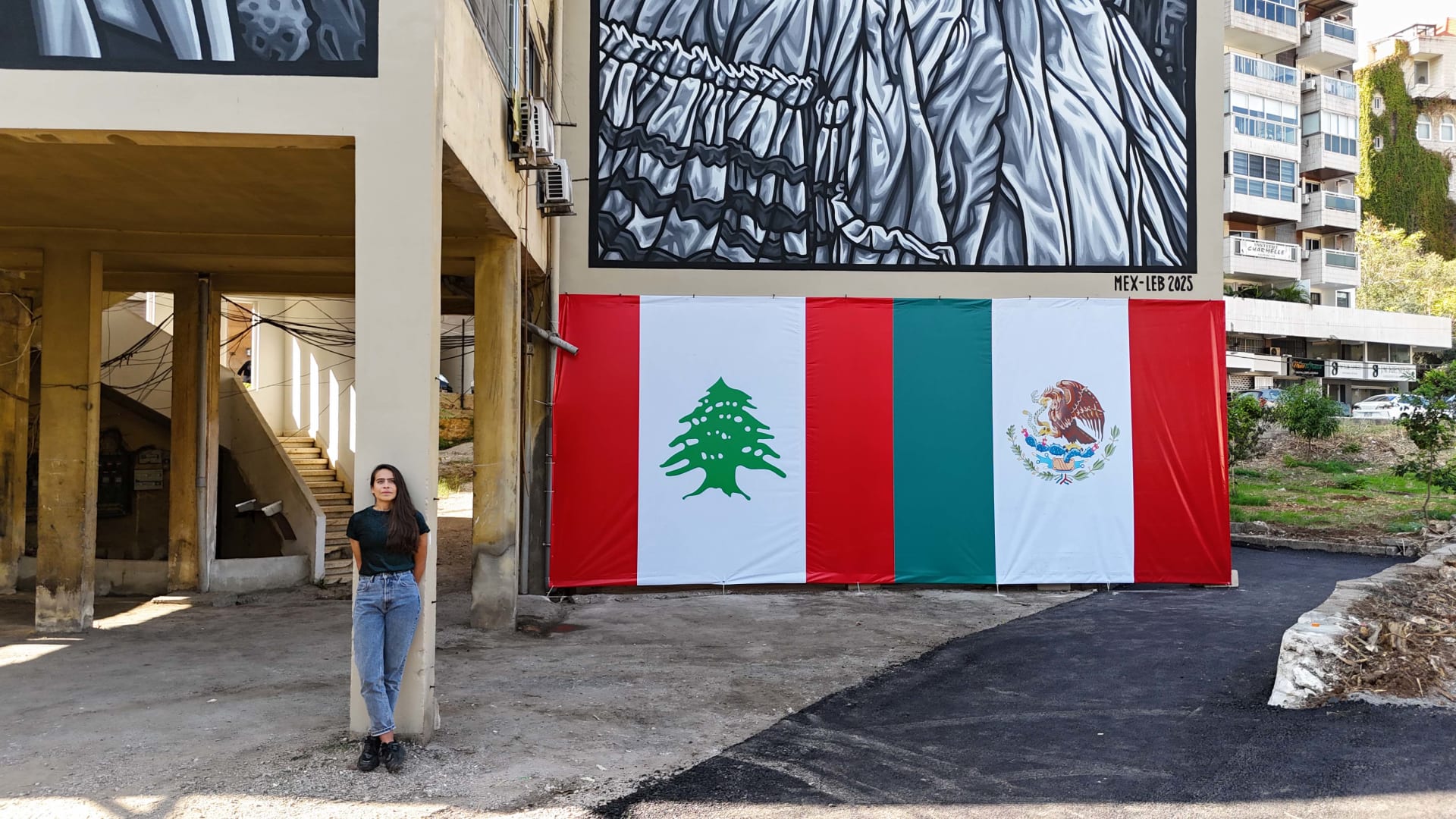 باولا دلفين تقف أمام الجدارية التي رسمتها في مدينة جونية اللبنانية.