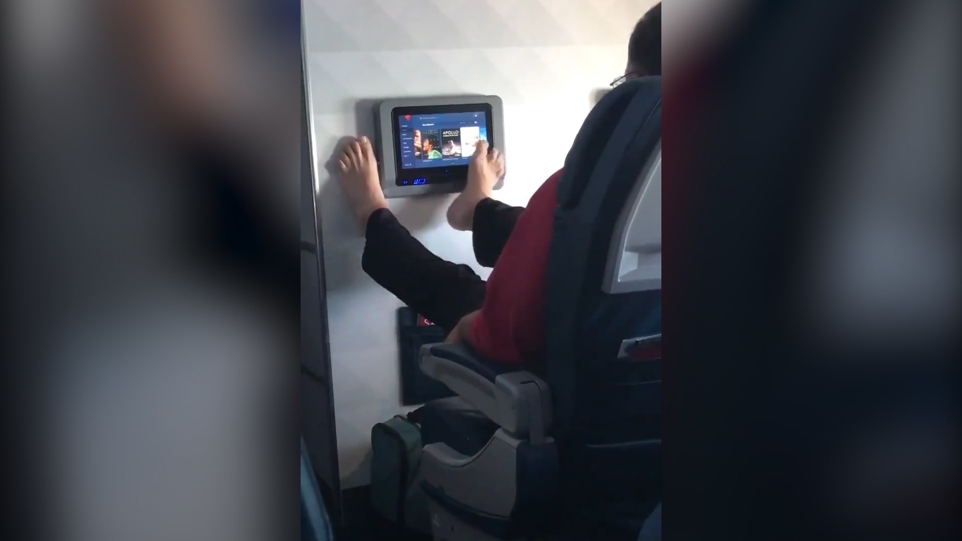 مسافر يستخدم شاشة الطائرة بقدميه