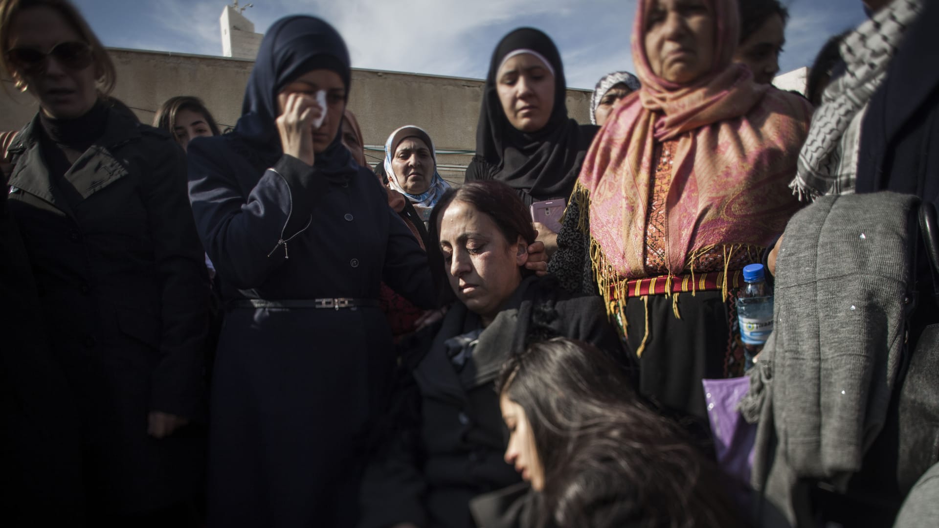 زوجة زياد أبو عين وابنته تجلسان قرب جثمانه قبل دفنه في رام الله.