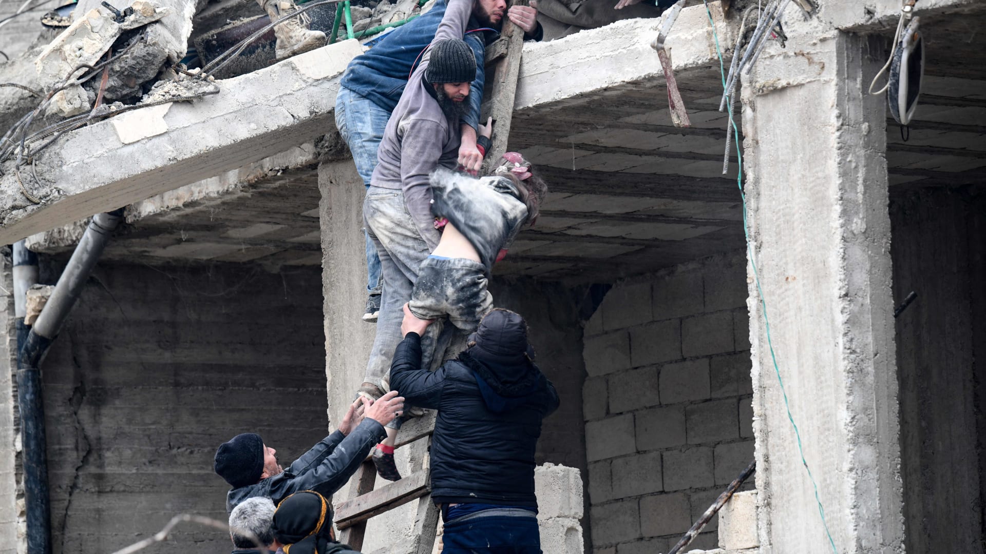 سكان ينتشلون طفلة من تحت أنقاض مبنى منهار إثر زلزال ضرب بلدة جنديريس بريف مدينة عفرين شمال غربي سوريا
