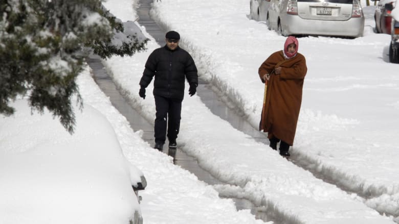 رجلان أردنيان يمشيان في شارع تغطيه الثلوج في عمان رجلان أردنيان يمشيان في شارع تغطيه الثلوج في عمان
