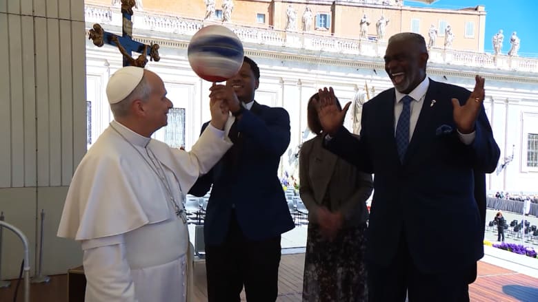 البابا لاوُن يُدير كرة سلة على إصبعه خلال استقبال فريق "هارلم غلوبتروترز" الاستعراضي