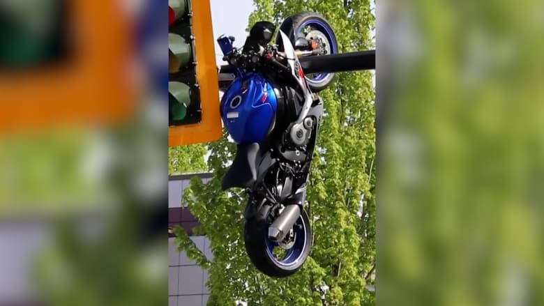 مشهد صادم.. دراجة نارية تتدلى من عمود إشارة مرور بعد حادث تصادم