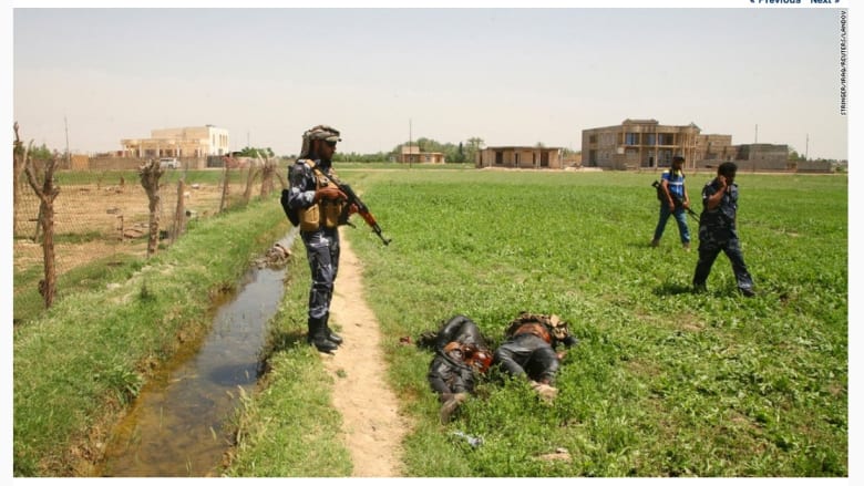 قوات الأمن العراقية تقف بالقرب من جثث أعضاء دولة العراق والشام الإسلامية  