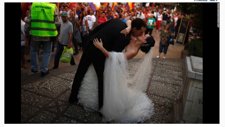 زوجان يتصوران خلال عرسهما في حديقة عامة بإسبانيا شجعتهما مجموعة من المحتجين في مسيرة مناهضة للنظام الملكي على تقبيل بعضهما.
