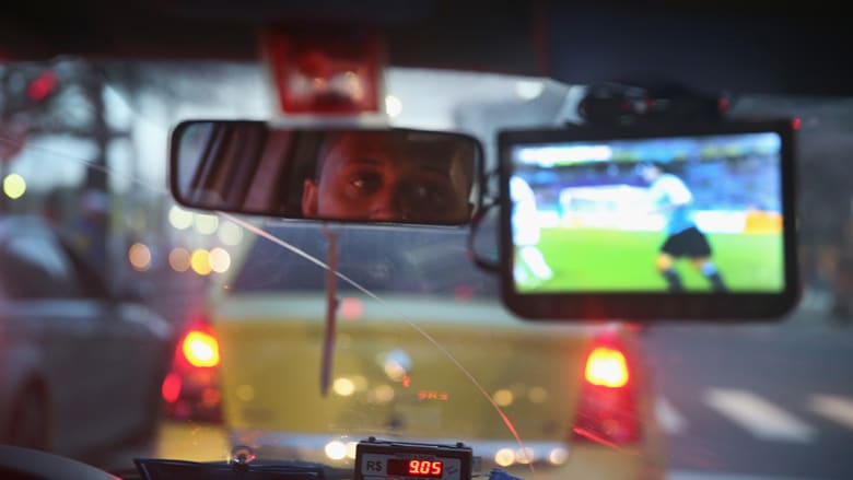 سائق يشاهد مباراة  كوستا ريكا وأوروغواي في سيارة الأجرة.