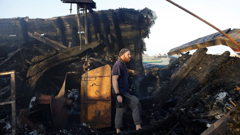 الكندي جون غودفري يتفقد الأضرار التي لحقت بقارب محترق لناشطي سلام بعد اصابته في غارة إسرائيلية