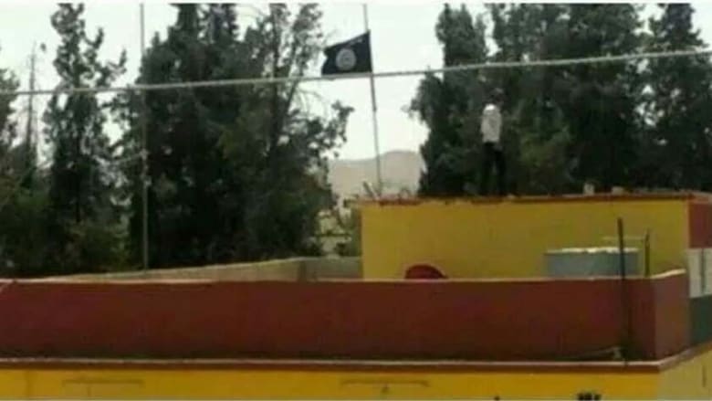 علم "الدولة الإسلامية" يرفعه عناصر داعش على مبنى السد الذي سيطروا عليه