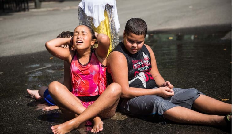 نيويورك، الولايات المتحدة-- طفلان يبتردان بجانب نافورة للمياه في نيويورك في ظل صيف حار تشهده المدينة 2 سبتمبر/ أيلول 2014