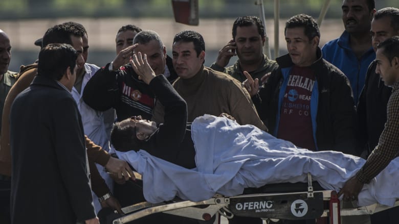 مبارك يحي الأشخاص من حوله بعد نقله من المروحية العسكرية إلى سيارة إسعاف 