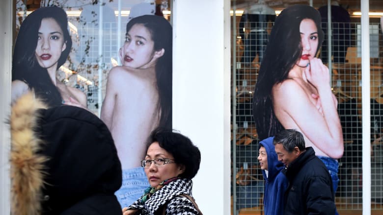 صينيون يمرون أمام فاترينات عرض بمحلات بعد الكشف عن تباطؤ نمو الاقتصاد للشهر الـثامن على التوالي