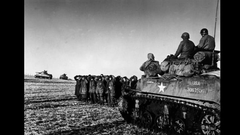 قوات أمريكية على متن دبابة يقف بجوارها أسرى حرب من الجنود الألمان