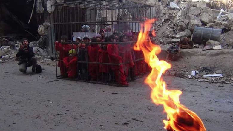 شاهد بالصور: أطفال دوما في قفص وشعلة النيران تنتظر لإحراقهم مثل الكساسبة باحتجاج على قصف الأسد