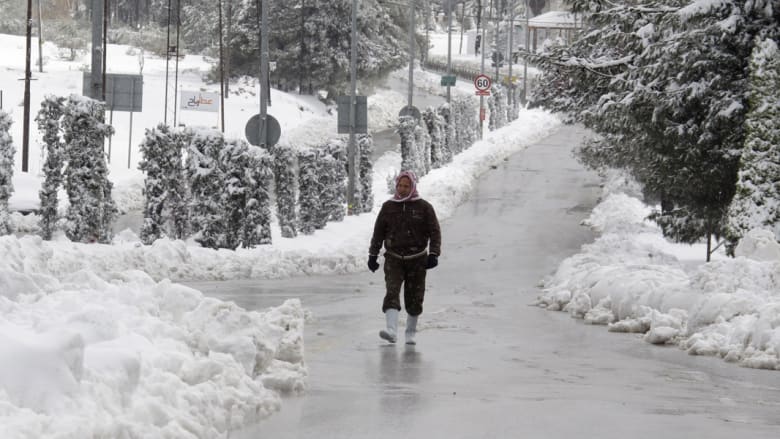 رجل يسير في شارع تغطيه الثلوج بعد عاصفة ثلجية ضربت العاصمة الأردنية عمان