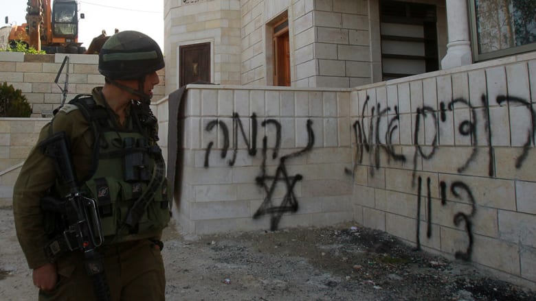 جندي إسرائيلي ينظر باتجاه عبارات مسيئة للعرب كتبت على جدران المسجد قرب بيت لحم.