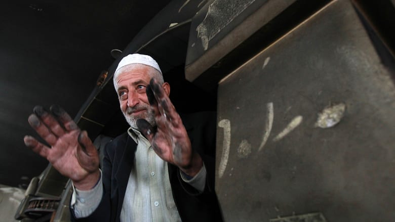 إمام المسجد يرفع يديه أمام عدسات المصورين لعرض آثار الرماد.
