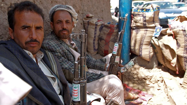 عدد من أنصار جماعة الحوثيين يحملون البنادق ويجلسون على قارعة الطريق في صنعاء.