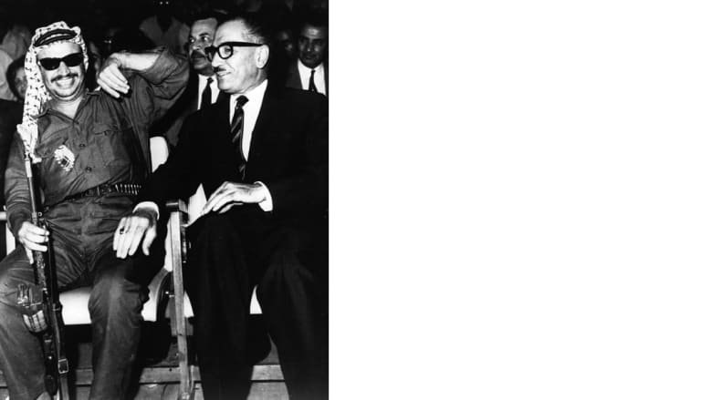 رئيس السلطة الوطنية الفلسطينية ياسر عرفات (يسار) يظهر وهو يحمل بندقية، وإلى اليمين رئيس وزراء الأردن عبدالمنعم الرفاعي، عمان الأردن، 12 أغسطس/ آب 1969