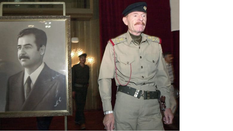 عزة إبراهيم الدوري في صورة التقطت بتاريخ 20 أغسطس/ آب 2001 وهو يمر بجانب صورة لصدام حسين لإلقاء كلمة في مؤتمر ببغداد