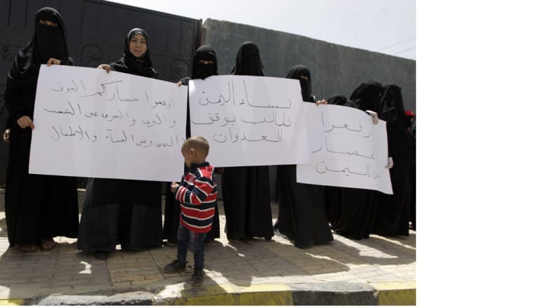 طفل يمني أمام سيدات يرفعن شعارات معارضة لعاصفة الحزم في صنعاء 15 أبريل/ نيسان 2015