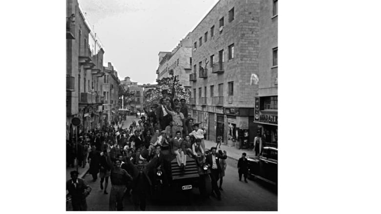 يهود من سكان القدس يلوحون بالعلم الذي أصبح فيما بعد علم إسرائيل، خلال احتقال أمام مبنى الأمم المتحدة بقرار التقسيم 30 نوفمبر/ تشرين الثاني 1947
