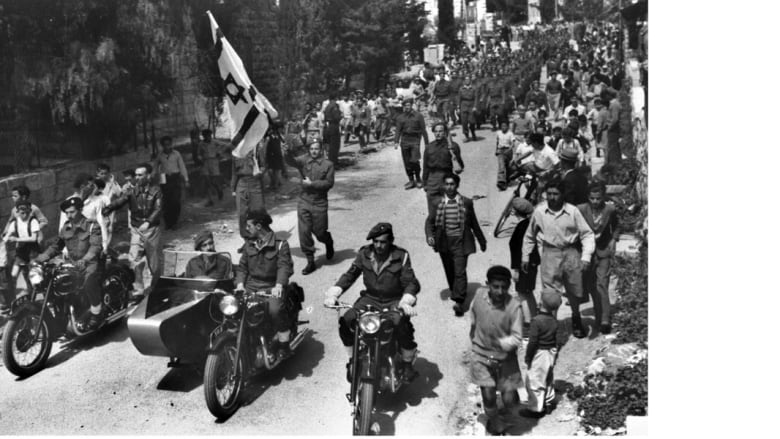 مقاتلون من الهاغاناه الإسرائيلية في مسيرة يرفعون خلالها العلم الإسرائيلية في شوراع القدس الغربية خلال الانتداب البريطاني 1 أبريل/ نيسان 1948