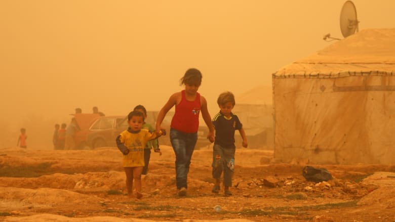 أطفال سوريون أثناء العاصفة الرملية في مخيم للاجئين على مشارف مدينة بعلبك شرق لبنان