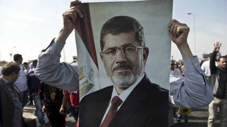مرسي يحيي الشعب بمحكمة "وادي النظرون".. والمحكمة ترد: "تاني.. مالكش دعوة بالشعب"