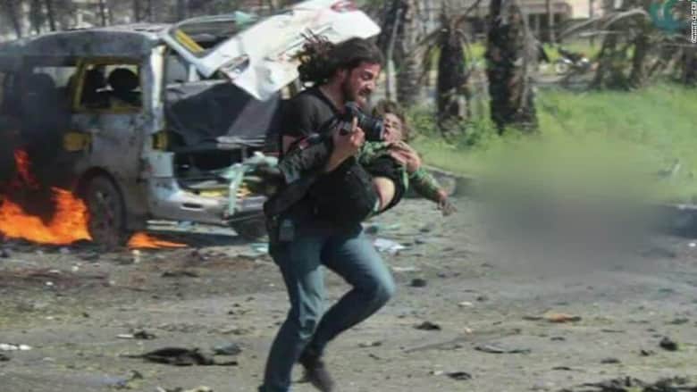 مصور سوري يحمل على يديه طفلاً أنقذه.. وكاميرا