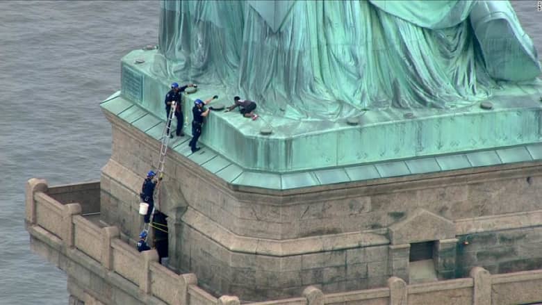 بذكرى الاستقلال.. شاهد امرأة تتسلق تمثال الحرية احتجاجاً