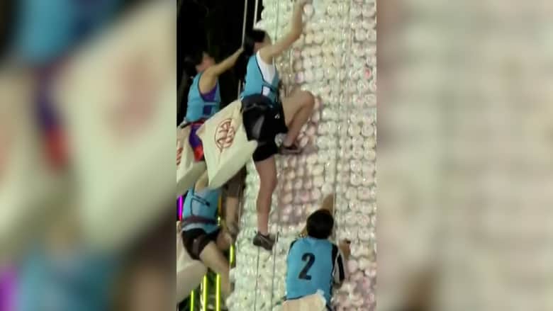 شاهد.. متنافسون يتسلقون قمة برج شاهق زُين بالكعك البلاستيكي